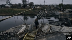 O femeie trece un pod aruncat în aer în Bahmut, Ucraina, regiunea Donețk, Ucraina, vineri, 11 noiembrie 2022.