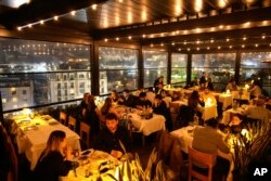 Njerëzit duke darkuar dhe duke pirë raki - pije alkoolike popullore turke - në një restorant me ushqime deti në lagjen Karakoy, në Stamboll, 23 mars 2024.