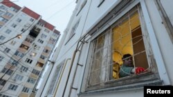 Ruskinja uklanja razbijeno staklo sa svog prozora nakon napada dronom u Voronježu, Rusija 16. januara 2024.