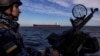 Un militar al gărzii de coastă a Ucrainei în timpul unei patrule, în timp ce o navă de marfă în larg în Marea Neagră, februarie 2024.