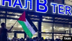 Lokalni čovjek maše palestinskom zastavom s porukom "Dagestan s vama", na aerodromu Mahačkala, Dagestan, Ruska Federacija, 29. 10. 2023.