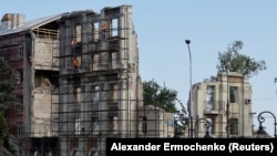 Építőmunkások dolgoznak egy épület maradványain az oroszok által megszállt Mariupolban, Ukrajnában, 2023. augusztus 16-án.