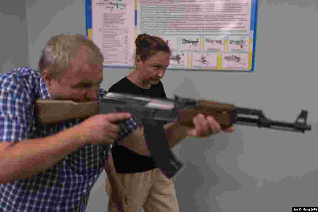 Instructorul Oleksi Oghirenko îi arată Irinei Ciudna cum să țintească cu un pistol-mitralieră în timpul antrenamentului cu arme de foc.