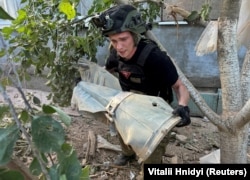 Një pjesëtar i ushtrisë ukrainase duke bartur pjesë të një bombe ruse që është hedhur në Harkiv.