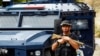 Një zyrtar policor duke qëndruar pranë automjetit të dëmtuar të Policisë së Kosovës, pas sulmit të 24 shtatorit 2023 nga një grup i armatosur në fshatin e veriut të Kosovës, Banjskë.