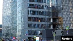 Сотрудники экстренных служб собираются возле повреждённого офисного здания в «Москва-Сити» после сообщения об ударе беспилотником в Москве. Россия, 30 июля 2023 года