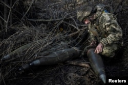 Un soldat ucrainean al Brigăzii 55 de Artilerie pregătește obuze de 155 mm în apropierea orașului Marinka din prima linie a frontului din regiunea Donețk, în decembrie 2023.