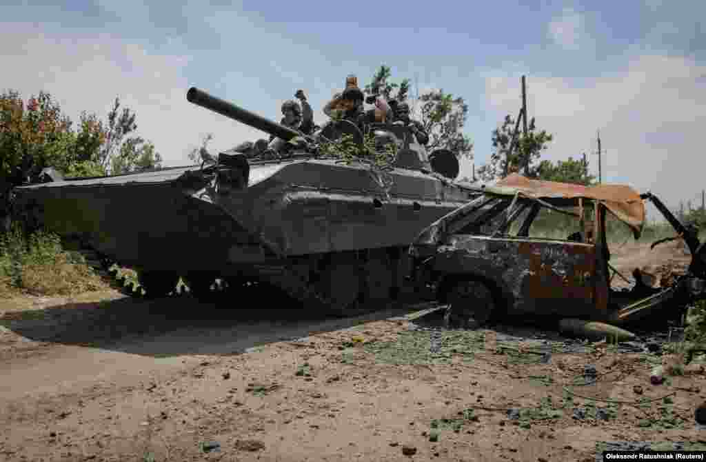 Ukrajinski vojnici na BMP-1 borbenom vozilu pored uništenog automobila u selu.