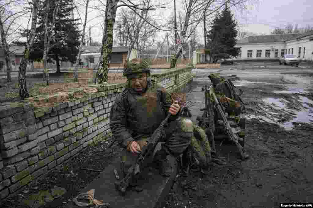Un soldat ucrainean venit din prima linie a frontului de la Bahmut, curăță noroiul de pe armă. &nbsp;