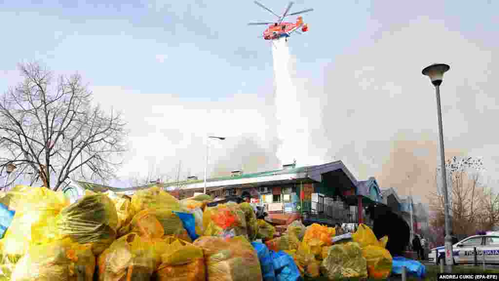 Prodavci spašavaju svoju robu dok helikopter ispušta vodu na požar u "Kineskom tržnom centru" u Beogradu 24. januara.