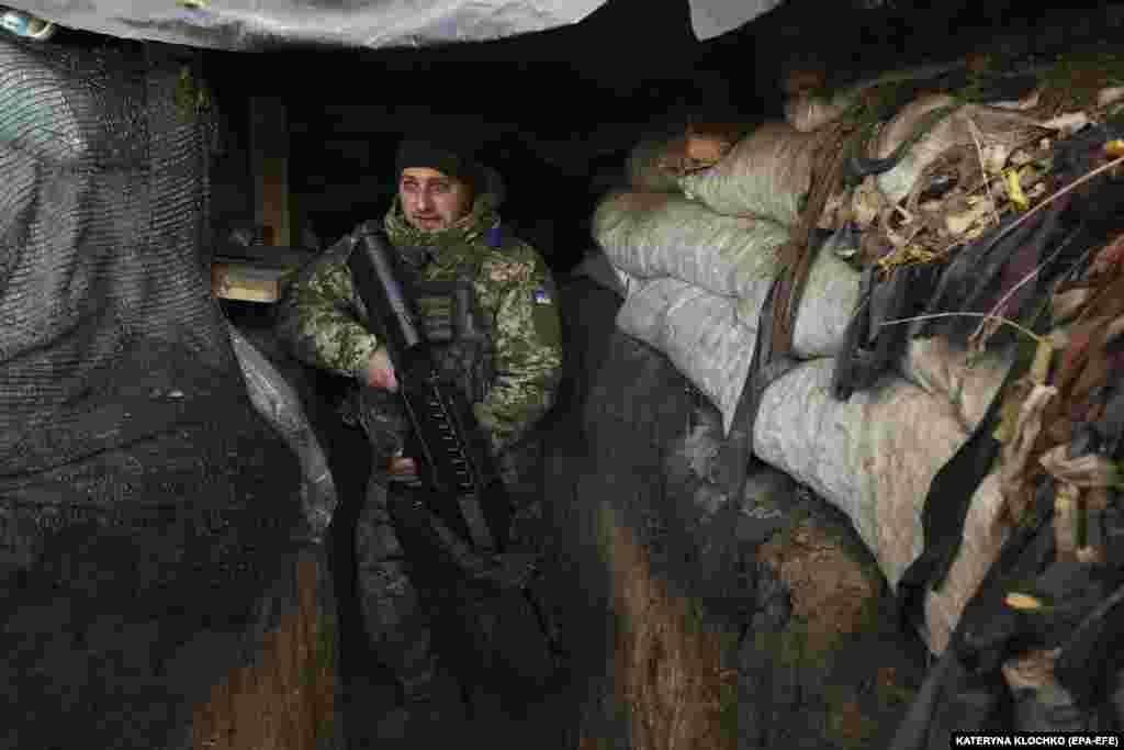 Un soldat ucrainean cu o pușcă antidronă patrulează tranșeele ocupate cândva de forțele rusești.