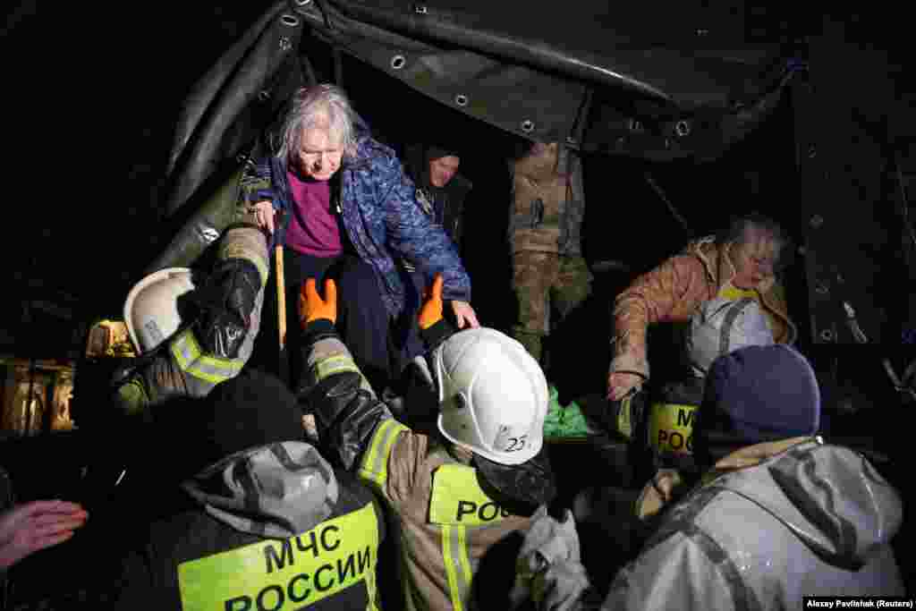 Localnicii sinistrați sunt ajutați de salvatori să coboare dintr-un camion după o evacuare de urgență de pe o stradă inundată din orașul Evpatoria din Crimeea, pe 26 noiembrie. Oleg Kriucikov, oficial rus instalat în regiunea pe care Moscova a anexat-o de la Ucraina în 2014, a declarat că o persoană a murit în urma inundațiilor. 