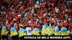 Lojtarët e Dinamo Kievit hyjnë në fushë me flamuj kombëtarë ukrainas, gjatë një ndeshjeje kundër SL Benfica-s në Portugali, më 23 gusht, 2022.