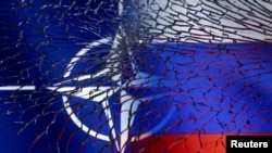 NATO and Russian flags are seen through broken glass in this illustration taken March 1, 2022.