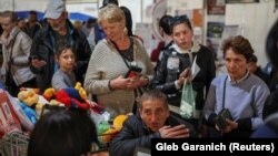Бегалци од Мариупол стојат во ред за финансиска помош по пристигнувањето во центарот за регистрација и хуманитарна помош за внатрешно раселените лица во Запорожје, Украина, 8 мај 2022 година.