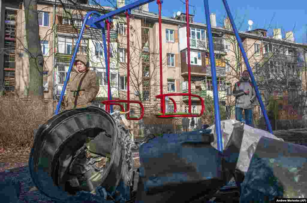 Stanovnici Harkova stoje pored dijelova vojne opreme na ulici nakon očiglednog ruskog vazdušnog napada na taj ukrajinski grad.