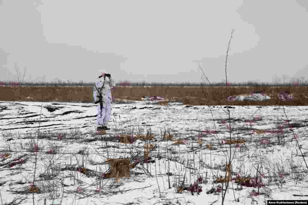 A Ukrainian soldier in snow camouflage peers toward the positions of Russia-backed separatists in the Donetsk region on January 21.&nbsp;