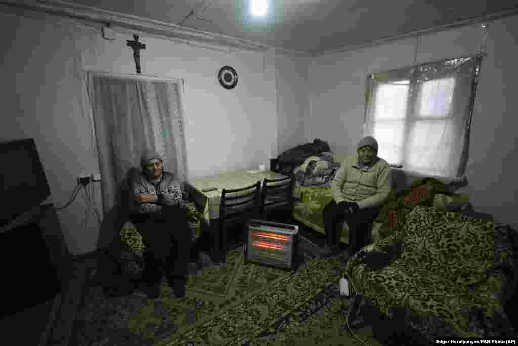 Două femei în vârstă se încălzesc lângă un radiator în Stepanakert. &nbsp;
