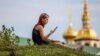 O femeie se uită în telefonul mobil. Pe fundal - biserici din orașul Suzdal, regiunea Vladimir, Rusia.