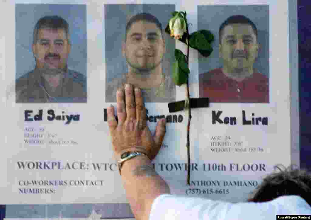 Spitalul Bellevue din New York, 16 septembrie 2001 - Un bărbat atinge un perete cu fotografii ale celor dispăruți în atacurile de la World Trade Center. Primii salvatori și lucrătorii din serviciile de urgență, dintre care mulți și-au pierdut colegi, membri din familie și prieteni, și-au continuat eforturile luni de zile pentru a recupera rămășițe și pentru a curăța locul. 