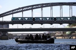 Membri ai brigăzii de elită a poliției franceze, RAID, stau într-o barcă gonflabilă în timpul unui test operațional pentru ceremonia de deschidere a Jocurilor Olimpice de la Paris 2024, iulie 2023, Paris.