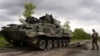 Një ushtar ukrainas kalon pranë një tanku të shkatërruar rus. Harkiv, 15 maj 2022.