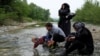 A group of people who tried to cross the Greek-Macedonian border takes a rest after crossing a small river on their way back to a makeshift camp for refugees and migrants at the border near the village of Idomeni, Greece, May 12, 2016. 