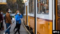A koronavírus járvány miatt védőmaszkot viselő utasok a budapesti villamosmegállóban 2020. október 31-én.