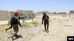 Afghan soldiers inspect the scene after overnight clashes with Taliban militants at a military base in Kandahar Province on July 26.