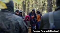 Iraki migránsok csoportja a belarusz–lengyel határ lengyel oldalán határőrök és rendőrök gyűrűjében. Hajnówka, 2021. október 14.