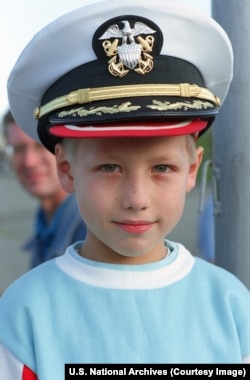 Un băiat rus poartă o șapcă de ofițer naval american în Vladivostok.