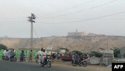 Pakistan -- Pakistani residents watch from a road the five-star Pearl Continental hotel, located on a hill (top back) in the southwestern Pakistani city of Gwadar, on May 11, 2019. 