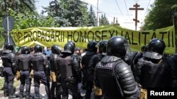 Polițiști în fața unui banner anti-LGBT la Chișinău, la 16 iunie 2024.