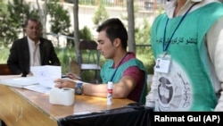 FILE: Employees of the Independent Election Commission registers a voter for the upcoming parliamentary and district council elections in Kabul.