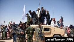 FILE: Afghan Taliban militants and residents stand on an armored Humvee vehicle of the Afghan National Army (ANA) as they celebrate a cease-fire in Maiwand district of Kandahar Province in June 2018.