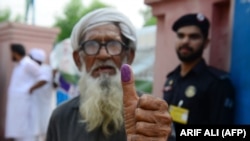 An elderly Pakistani man shows his inked thump after casting his vote outside a polling station during general election in Lahore on July 25.