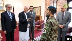 Afghan President Ashraf Ghani (2 - L) presents Afghan Army soldier, Esa Khan (C) with the keys to a new flat in recognition of his bravery in an attack by armed fighters on the Afghan Parliament in June 23.