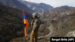 NAGORNO-KARABAKH -- An ethnic Armenian soldier stands guard next to Nagorno-Karabakh's flag atop of the hill near Charektar in at a new border with Kelbajar district turned over to Azerbaijan, November 25, 2020.