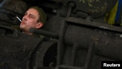 Член на украински танков екипаж чака механиците да ремонтират танка му, след като се е върнал от мисия на фронтовата линия в Бахмут на 3 април.