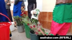 O pagină de ziar în care apare fostul președinte al Turkmenistanului, Gurbanguly Berdymukhammedov, este folosită pentru a împacheta flori.