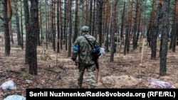 Një ushtar ukrainas duke hetuar një varrezë masive afër Izjumit.