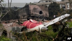 Părți dintr-un avion Air India prăbușit joi sunt văzute deasupra unei clădiri din Ahmedabad, India, vineri, 13 iunie 2025.