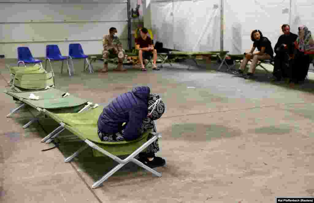 O femeie stă pe un pat pliant în adăpostul temporar aflat în cazarma armatei americane „Rhine Ordonanz" din Kaiserslautern, Germania.