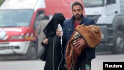 A man carries a child with an IV drip as he flees deeper into the remaining rebel-held areas of Aleppo on December 12.