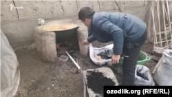 Un bărbat pune cărbune într-un cuptor în aer liber în Uzbekistan. (poză de arhivă)