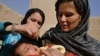 An Afghan woman holds a child as a health worker administers the polio vaccine. The WHO says that large-scale immunization can stop an outbreak.