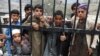 FILE: Stranded travllers wait to cross into Pakistan from Afghanistan at the Torkham border in March.