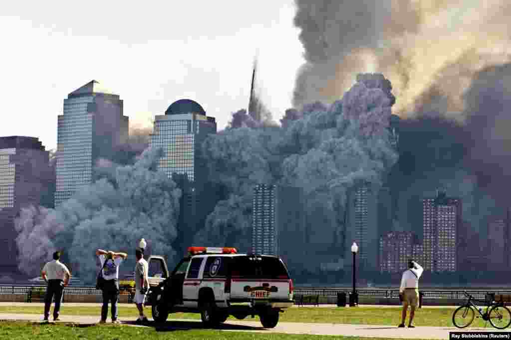 Trecătorii și poliția privesc cum se dezintegrează într-un nor de praf și resturi al doilea turn al World Trade Center din New York. Momentul a fost la aproximativ 30 de minute după prăbușirea primului turn. 