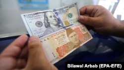 A Pakistani money changer holds Pakistani rupee and U.S. dollar bills in Peshawar on May 16.
