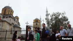 Disa qytetarë duke dalë nga xhamia në Ferizaj, në oborrin e së cilës gjendet edhe një kishë ortodokse.